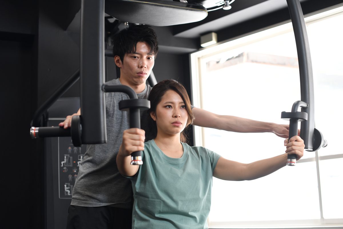 チェストプレスのやり方をトレーナーが指導している様子